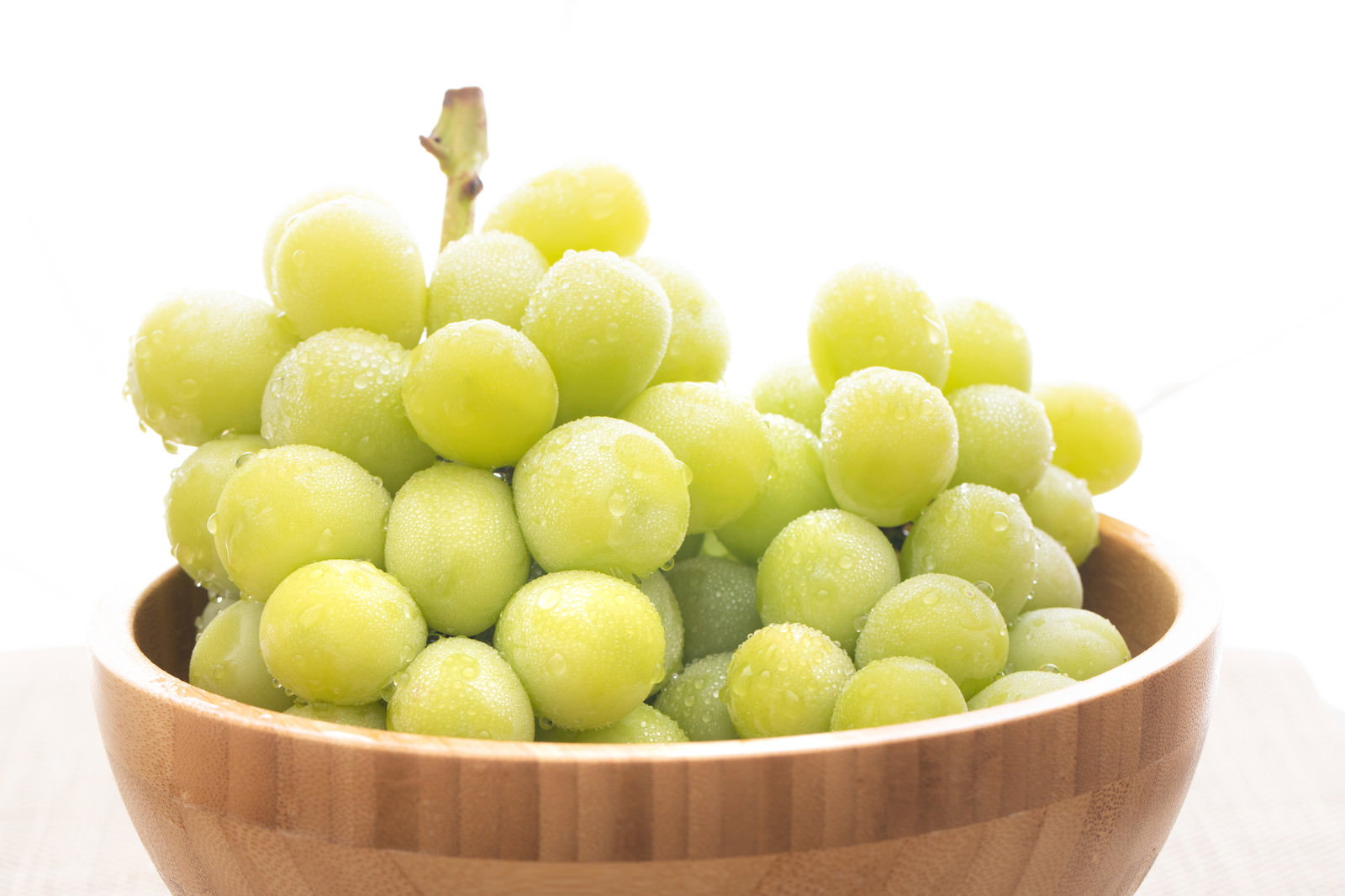 木製のボウルに盛られた新鮮なシャインマスカットの房