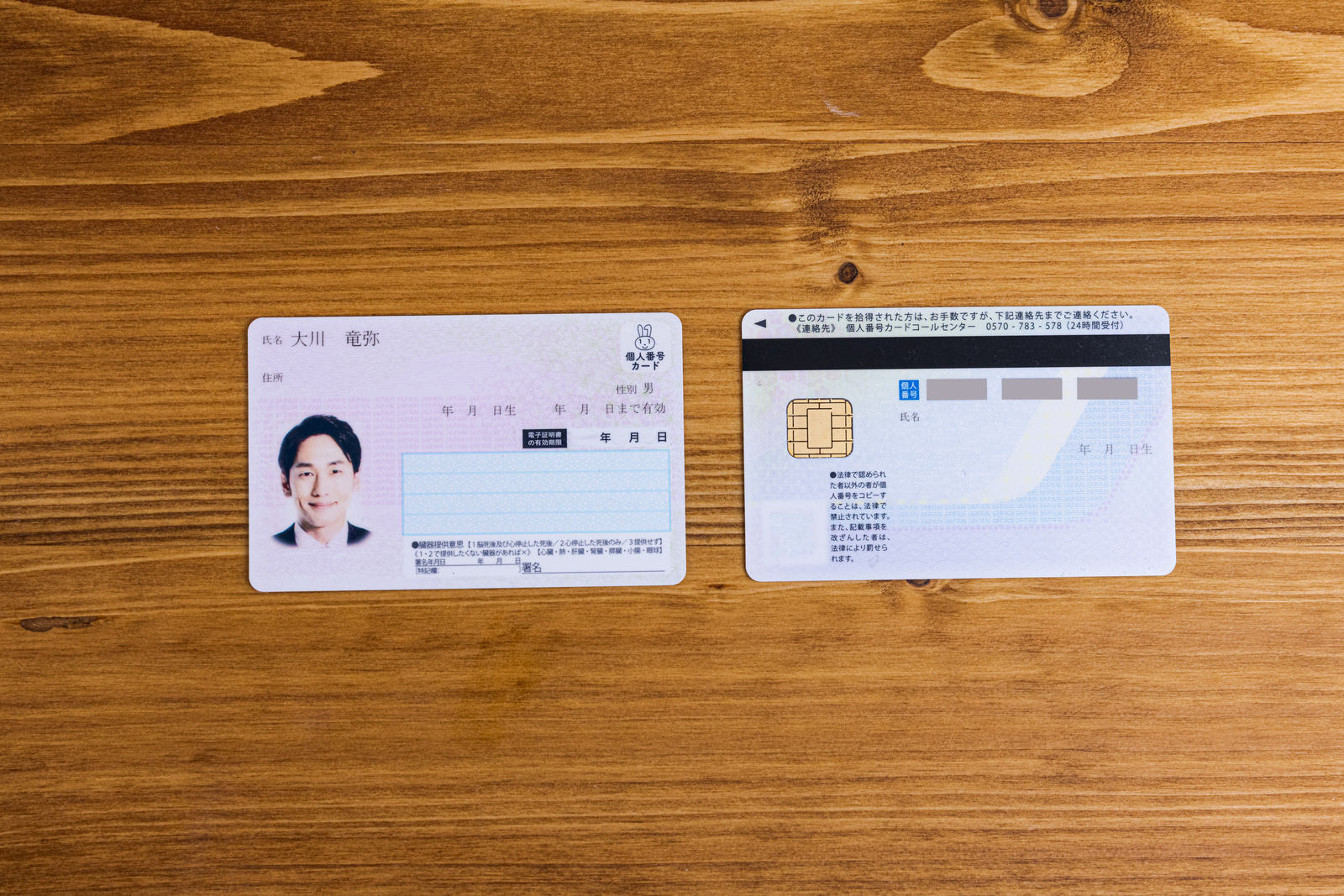 木製テーブルに置かれたマイナンバーカードの表面と裏面