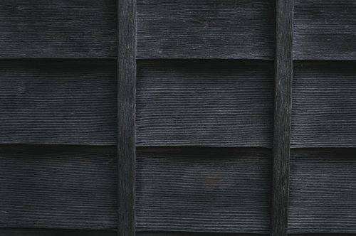 雨よけの木の壁、濃いグレーの縦板張り外壁