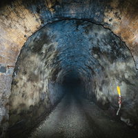 奥深くまで続く暗いトンネル、石造りのアーチが連なる長野原町の坑道の写真