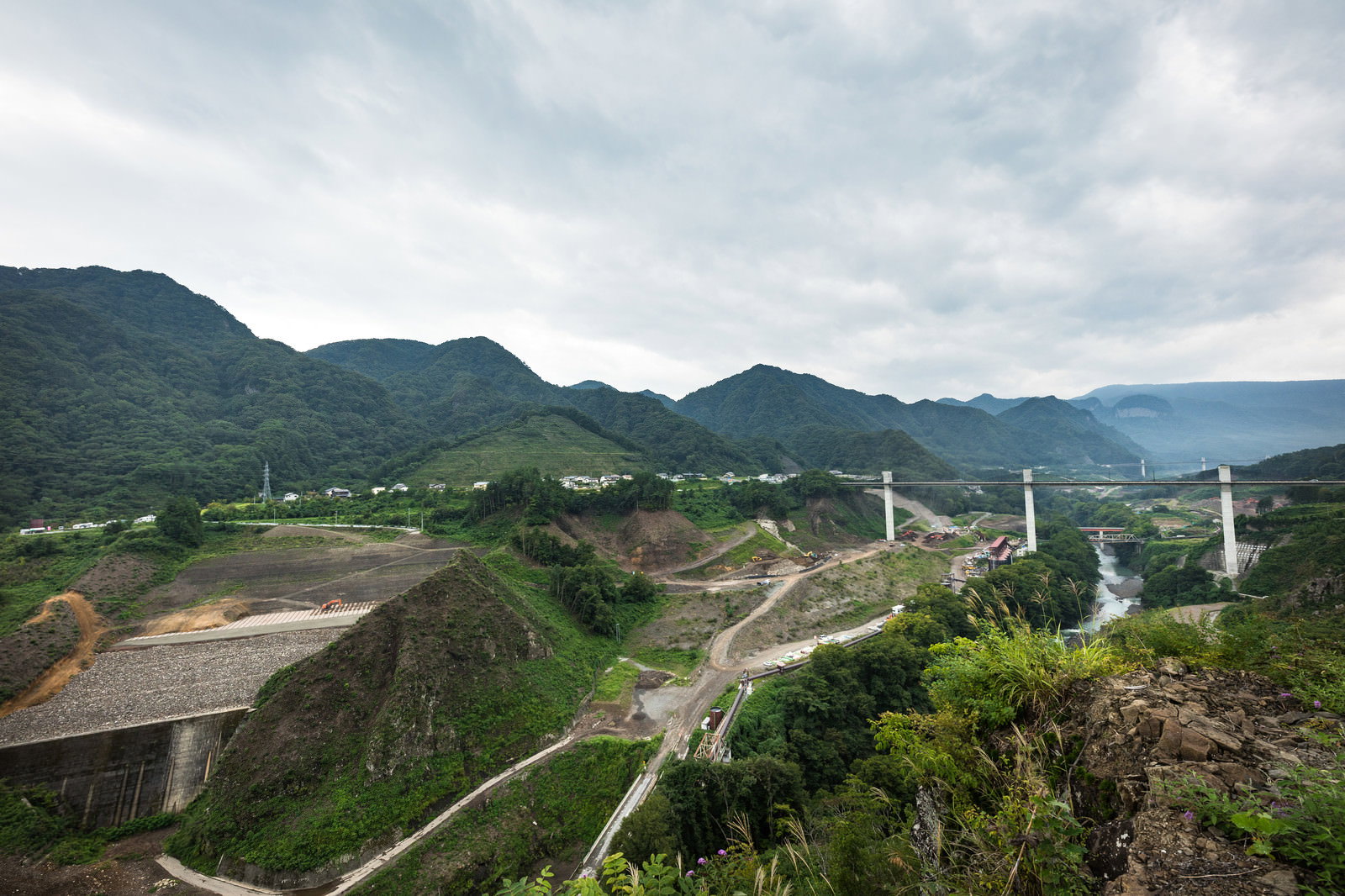 やんば見放台から撮影した八ッ場ダム建設地の全景、緑の山間部に橋梁や工事現場が見える風景