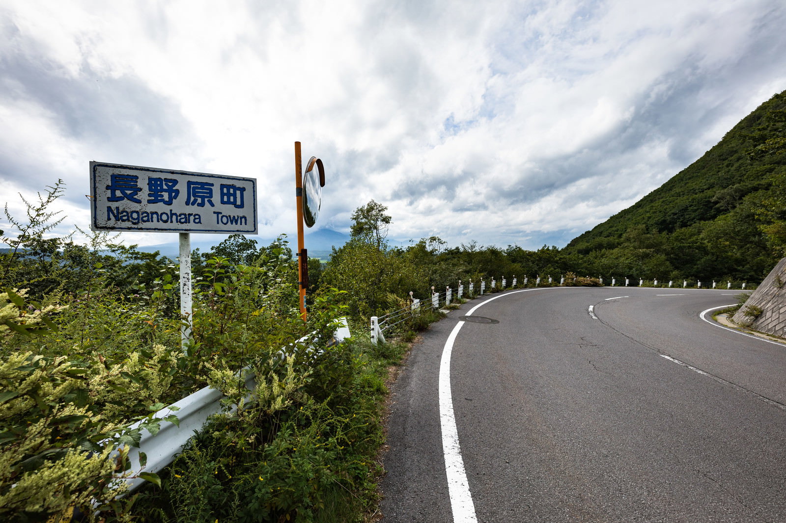 二度上峠の急カーブに立つ道路標識とガードレールのある山道