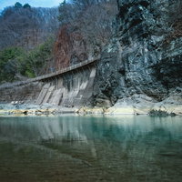 吾妻川に聳える川原湯岩脈（臥龍岩）と清流の景観の写真