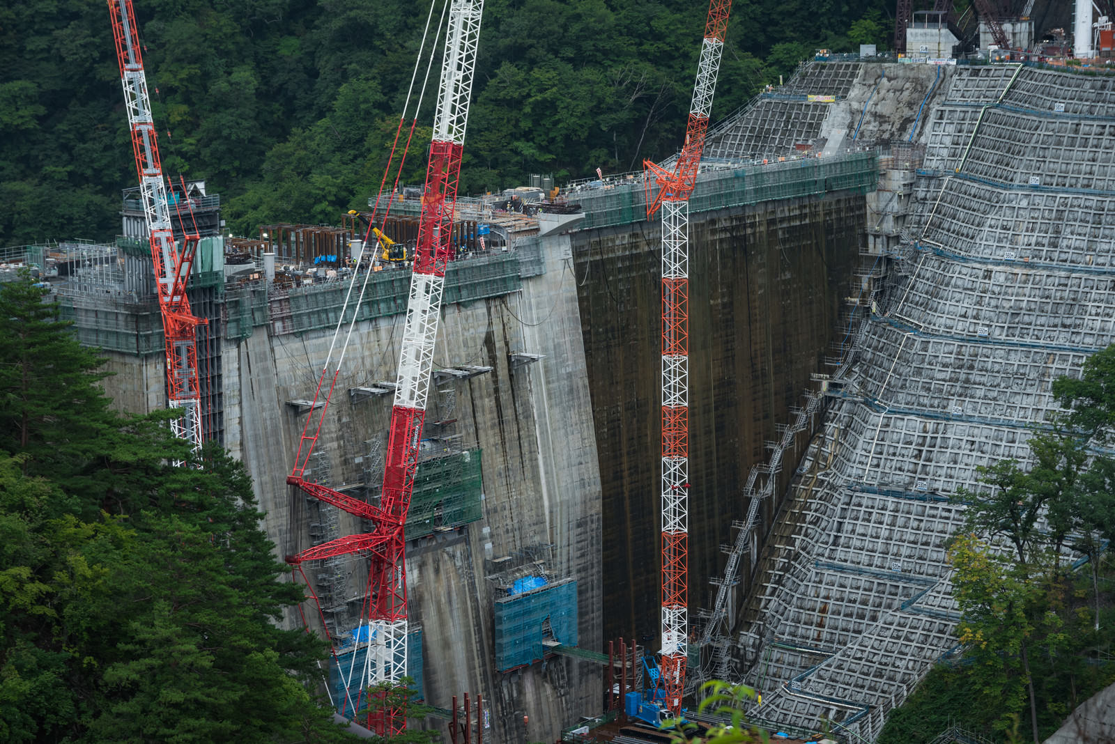 八ッ場ダムの建設現場で稼働する複数の赤いクレーンとコンクリート構造物