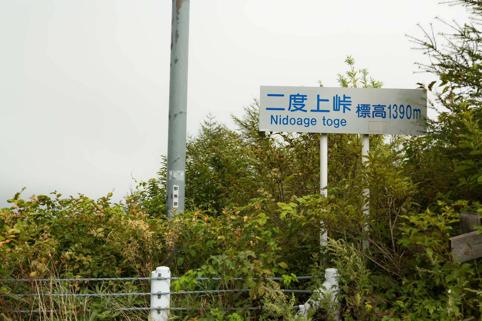 青い道路標識に「二度上峠」と書かれた山間部の風景
