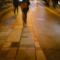 夜遅い帰りみち、街灯に照らされた歩道を歩く人物の写真