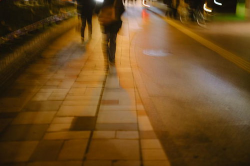 夜遅い帰りみち、街灯に照らされた歩道を歩く人物