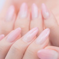 薄いピンク色に染まったネイルアート、整えられた爪の写真