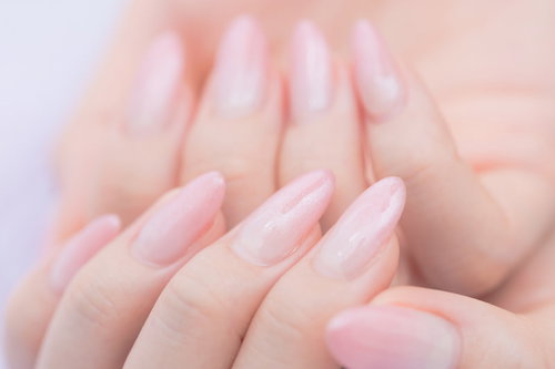 薄いピンク色に染まったネイルアート、整えられた爪