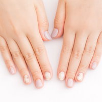 淡いピンクのジェルネイルアートを施した両手の写真