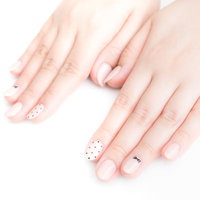 薄いピンクのベースに白いフラワーデザインのネイルをした爪の写真