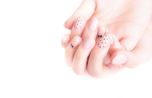 ピンク系ネイルをした女性の手先、上品なドット&ラインデザイン