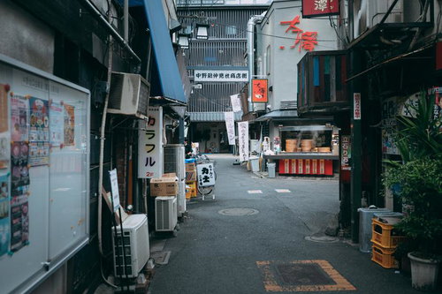 赤い看板と室外機が立ち並ぶレトロな商店街の小道