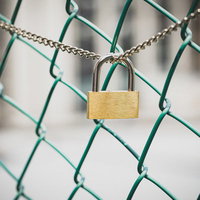 金色の南京錠が取り付けられたチェーンリンクフェンスの写真