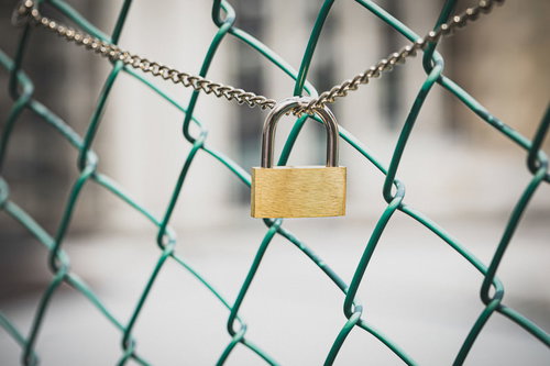 金色の南京錠が取り付けられたチェーンリンクフェンス