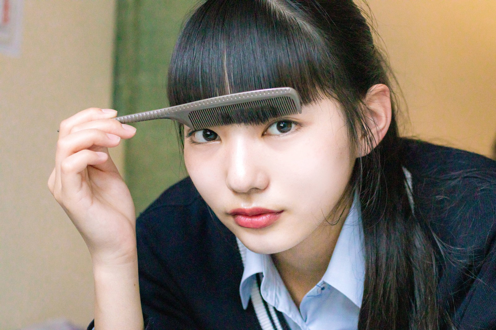 前髪にクシを通している制服姿の女子高生［モデル：なんこ］