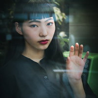 電話ボックスのガラス越しに凝視する女性の写真