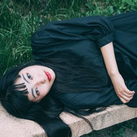 ベンチに寝転ぶ黒ワンピ女子の真顔でカメラ目線の写真