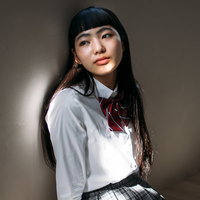 壁によりかかる学生女性、オン眉の女子高生ポートレートの写真