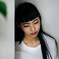 虚ろな表情でうつむくロングヘアの女性、悲しみと憂鬱の写真