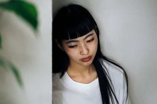 虚ろな表情でうつむくロングヘアの女性、悲しみと憂鬱