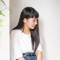 観葉植物の近くで控えめに座る人見知り端っこ女子の写真