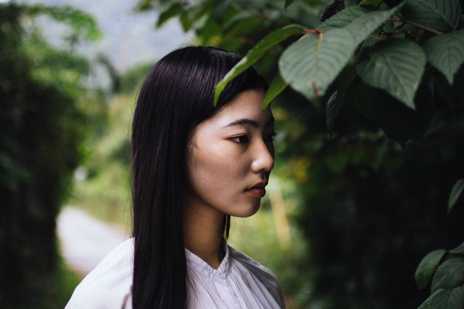木陰で物思いに耽る女性が遠くを見つめている［モデル：なんこ］