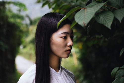 木陰でぼんやりと前を見つめる女性のポートレート