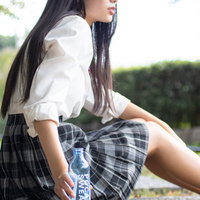 ベンチに座ってポカリで水分補給する女子高生の写真