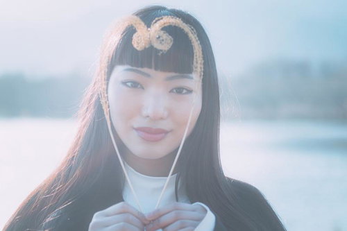 柔らかな光に包まれてハート型をつくる女性のポートレート