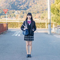 通学路で立ち止まる女子高生、山間地のセーラー服姿の写真