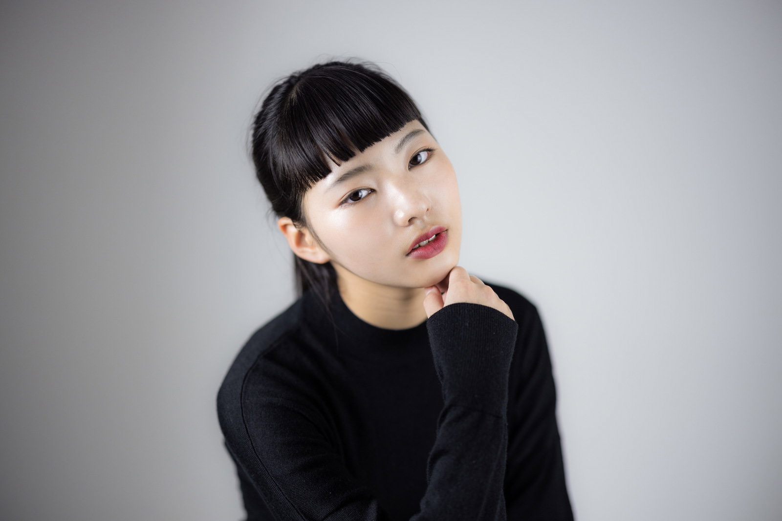 顎に手を添えてすまし顔をする黒髪オン眉の女性［モデル：なんこ］