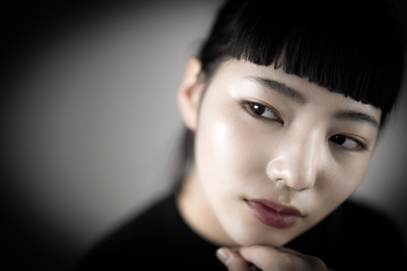 頬杖をついてオン眉の澄まし顔で横向きの女性［モデル：なんこ］