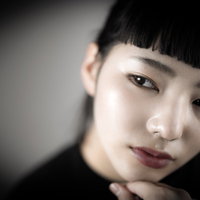 頬杖をついたオン眉の澄まし顔の女性のポージングの写真