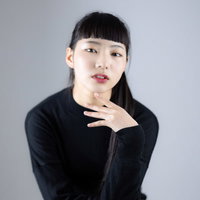 足を組んですまし顔でポーズをとる黒髪ショートボブの女性の写真