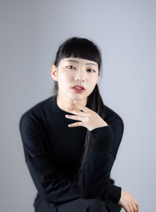 足を組んですまし顔でポーズをとる黒髪ショートボブの女性