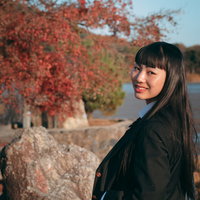 紅葉に包まれて後ろを振り返る長髪の女性の秋の風景の写真