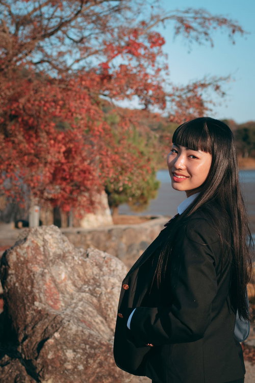 紅葉に包まれて後ろを振り返る長髪の女性の秋の風景