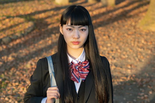 帰宅中の女子高生、秋の夕陽に包まれた学生服姿