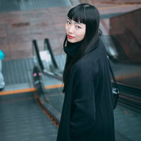 エスカレーターで後ろを振り返る黒髪の女性の写真