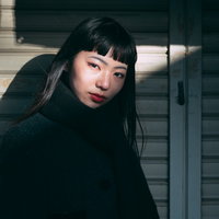 シャッター前で視線を向ける影と女性のオン眉ポートレートの写真