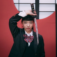 緑色の学生服姿の女子高生と日本刀を構えた和風コスプレの写真