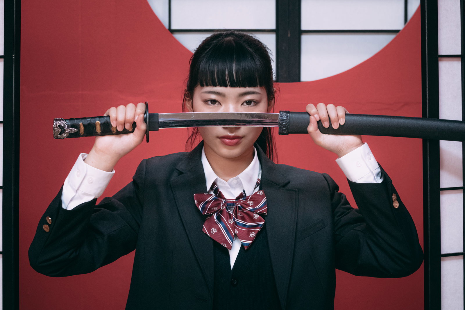 日本刀を両手で顔の前に構えるブレザー制服姿の女子高生［モデル：なんこ］