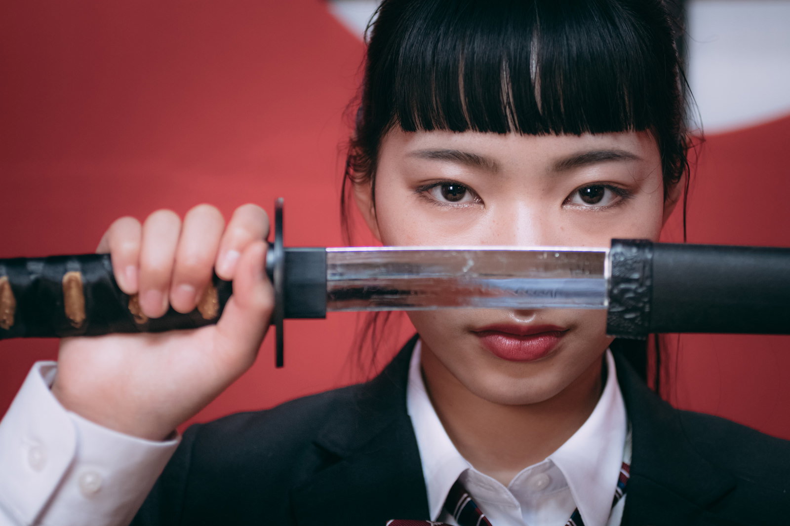 日本刀を顔の前に横に構えた女子高生［モデル：なんこ］