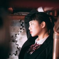 黒いスーツにオン眉のポニーテール、ツンとした表情の女性の横顔の写真