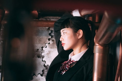 黒いスーツにオン眉のポニーテール、ツンとした表情の女性の横顔