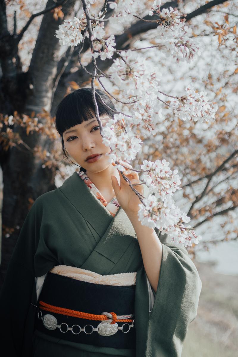 桜の枝に手を添える緑の着物の女性［モデル：なんこ］