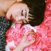 花びらに包まれて寝転ぶ女性のポートレートの写真