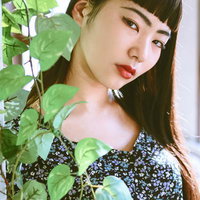 観葉植物越しからのポージング女子、赤リップで静かな表情の写真