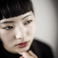 頬杖をついてツンとした表情のオン眉前髪の女性ポートレートの写真